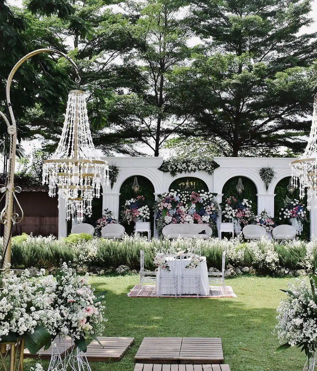 Wedding decor with chandeliers and white arches on the lawn