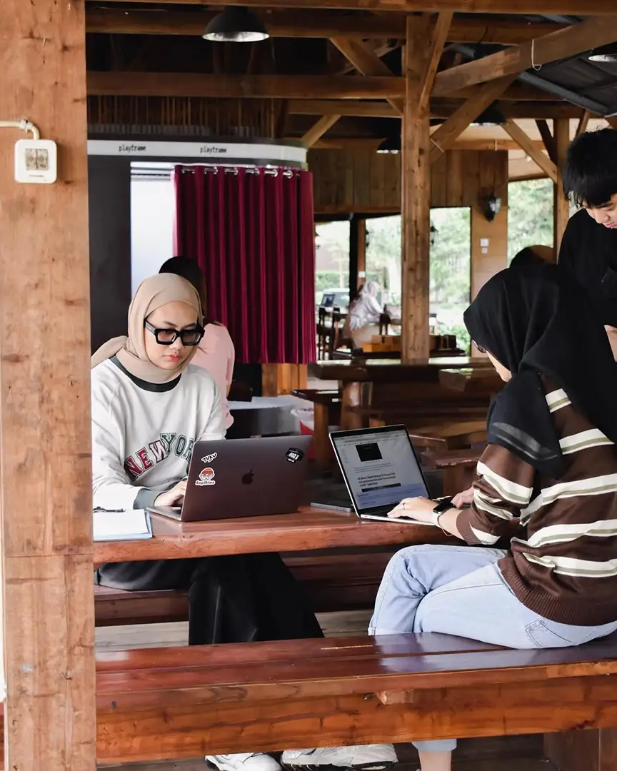 Guests working on laptops at long wooden tables in the pavilion